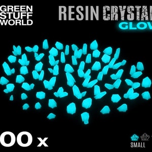 May include: 100 small glow-in-the-dark resin crystals. The crystals are a light blue color and are scattered on a black background.  RESIN CRYSTALS GLOW.