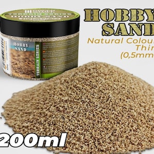 Może przedstawiać: Słoik o pojemności 200 ml z naturalnym piaskiem hobbystycznym, oznaczony jako "Hobby Sand" i "Terrain Series". Piasek jest cienki, o granulacji 0,5 mm.