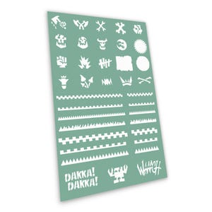 Op de afbeelding: Een saliegroen sjabloonvel met diverse witte uitgestanste ontwerpen, waaronder schedels, tandwielen, vlammen en gekartelde randen. Het vel bevat ook de tekst DAKKA! DAKKA! en WAAAGH! samen met een klein icoon van een robotachtige figuur.