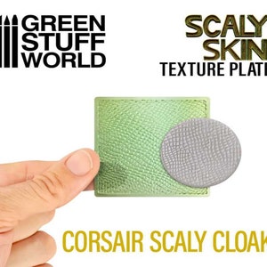 Op de afbeelding: Green Stuff World Schubbenhuid Textuurplaat. Een groene siliconen textuurplaat met een reliëf schubbenpatroon. De plaat wordt vastgehouden door een hand. De plaat wordt gebruikt om realistische schubbentexturen op modellen te creëren.