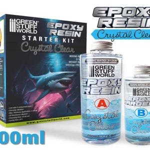 Może przedstawiać: Zestaw startowy do żywicy epoksydowej o krystalicznie czystym wyglądzie, z dwoma butelkami oznaczonymi 'A' i 'B', zawierającymi odpowiednio 200 ml i 100 ml żywicy. Zestaw zawiera grafikę rekina i tekst 'Green Stuff World Epoxy Resin Starter Kit Crystal Clear 300 ml'.