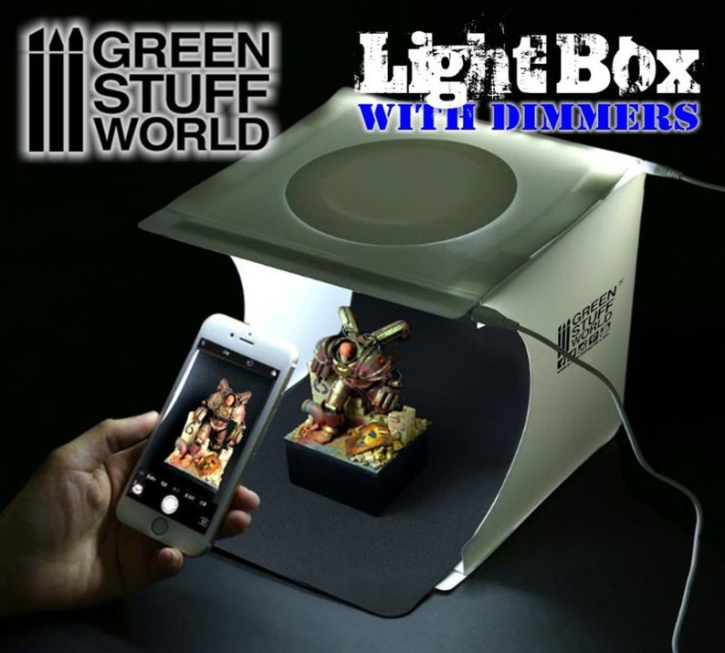Op de afbeelding: Een witte lichtbox met dimmers voor het fotograferen van kleine objecten. De lichtbox heeft een witte achtergrond en een zwarte vloer. Een klein model wordt gefotografeerd in de lichtbox. De lichtbox is gemaakt door Green Stuff World.