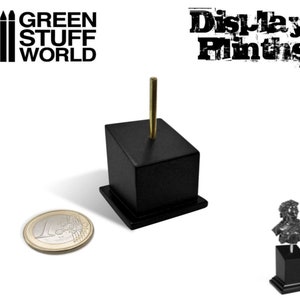 Puede incluir: Soporte de exhibición negro con una varilla de metal dorado para exhibir pequeñas figuras. El soporte tiene aproximadamente 5 cm de alto y una base cuadrada. Un pequeño soporte negro con una figura se muestra en el fondo.