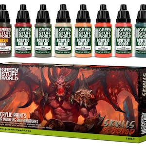 May include: A collection of Green Stuff World acrylic paints for modeling and miniatures. The image shows eight paint bottles in various colors, including red, orange, green, and beige, along with a box set featuring a demonic illustration. The box reads "Skulls & Blood".