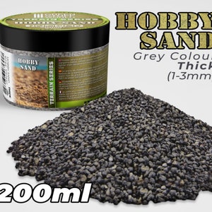 Op de afbeelding: Een pot van 200 ml grijze hobbyzand met een dikke textuur, ideaal voor modeltreinen en andere knutselprojecten. Het zand is 1-3 mm groot.
