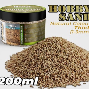 Może przedstawiać: Pojemnik o pojemności 200 ml z naturalnym piaskiem hobbystycznym. Piasek jest gruby, z ziarnami o wielkości od 1 do 3 milimetrów. Pojemnik jest oznaczony jako "Hobby Sand" i "Terrain Series".