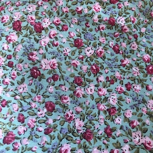 May include: A light blue fabric with a small pink and red floral pattern. The fabric is covered in tiny flowers.