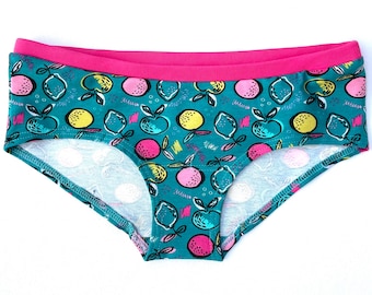 May include: Teal underwear with a pink waistband and a colourful fruit print. The print features lemons, apples and oranges.