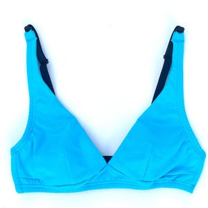 Può includere: Un top bikini turchese brillante con spalline nere. Il top ha un design a scollo a V ed è realizzato in un tessuto liscio e tinta unita. Le spalline sono regolabili ed è progettato per costumi da bagno.