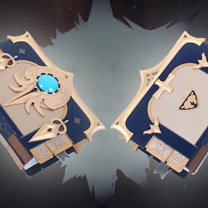 May include: Two closed books with blue covers and gold accents. One book has a turquoise gem and gold designs on the front cover. The other book has a gold design on the front cover.