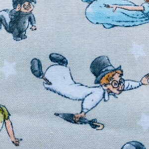 K&ouml;nnte beinhalten: Ein hellgrauer Stoff mit einem sich wiederholenden Muster von Figuren aus dem Film Peter Pan. Die Figuren sind Peter Pan, Captain Hook, Tinkerbell und Wendy. Der Stoff ist perfekt f&uuml;r Bastelprojekte wie Quilts, Kissen und Tragetaschen.