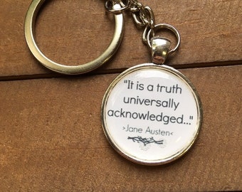 May include: A silver keychain with a round charm featuring the quote "It is a truth universally acknowledged..." by Jane Austen.