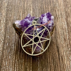 Peut inclure: Un pendentif en argent avec un motif d'étoile à huit branches, reposant sur un cristal d'améthyste violet.