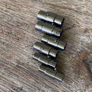 May include: A set of six black magnetic clasps for jewelry making. The clasps are made of metal and have a smooth, polished finish.