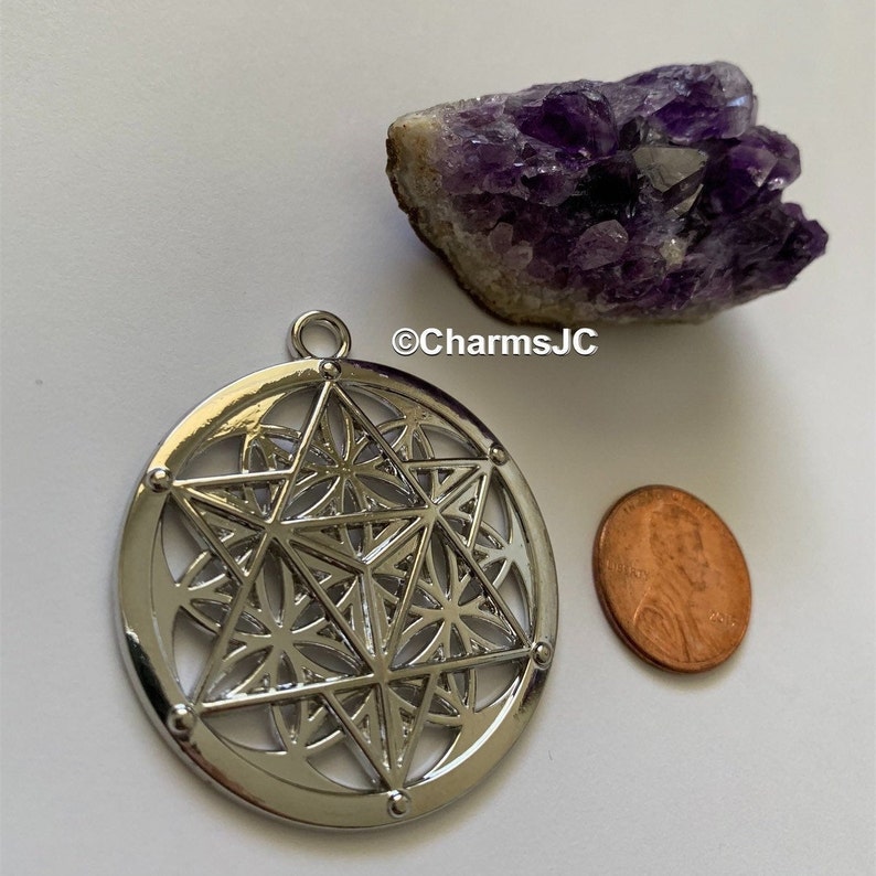 May include: Silver pendant with a geometric design featuring a star, circles, and triangles. The pendant is about the size of a UK penny.