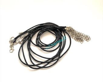 May include: A collection of black cord necklaces with silver-colored clasps and chain extenders. The cords are tightly wound and lie in a loose pile against a white background. The clasps are open and ready for use.