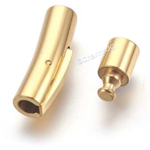 May include: Gold-toned metal bracelet clasp with a sliding mechanism. The clasp is made of two pieces, a curved bar and a cylindrical piece with a rounded end.