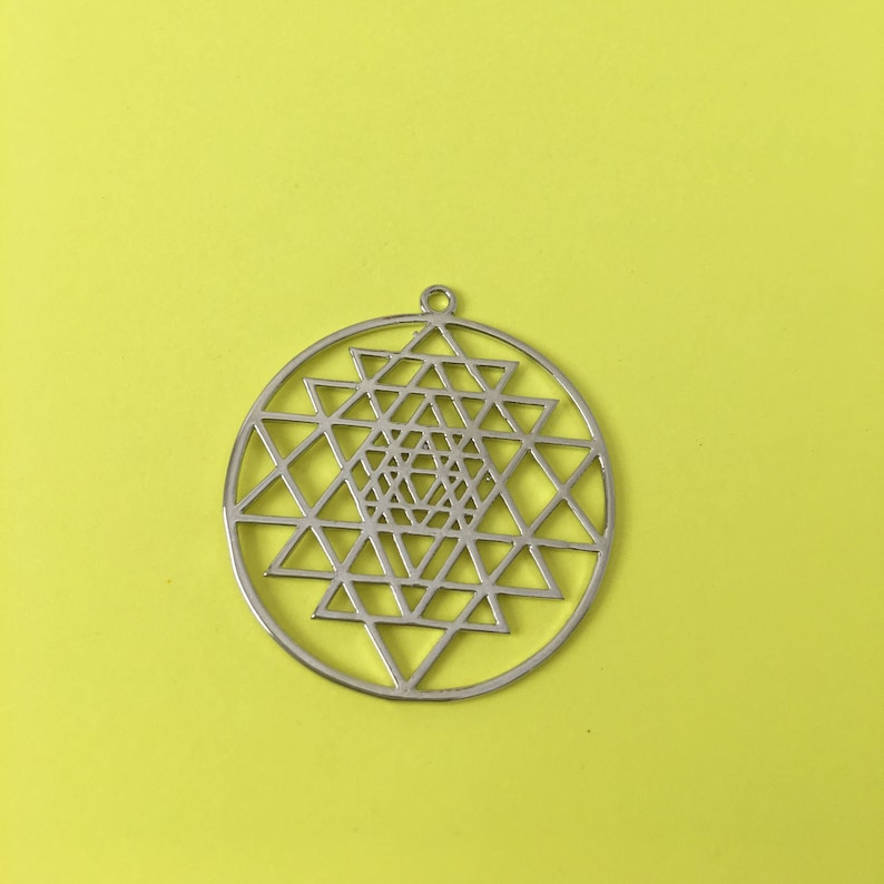 May include: A silver pendant featuring a Sri Yantra design, a geometric symbol representing the universe.