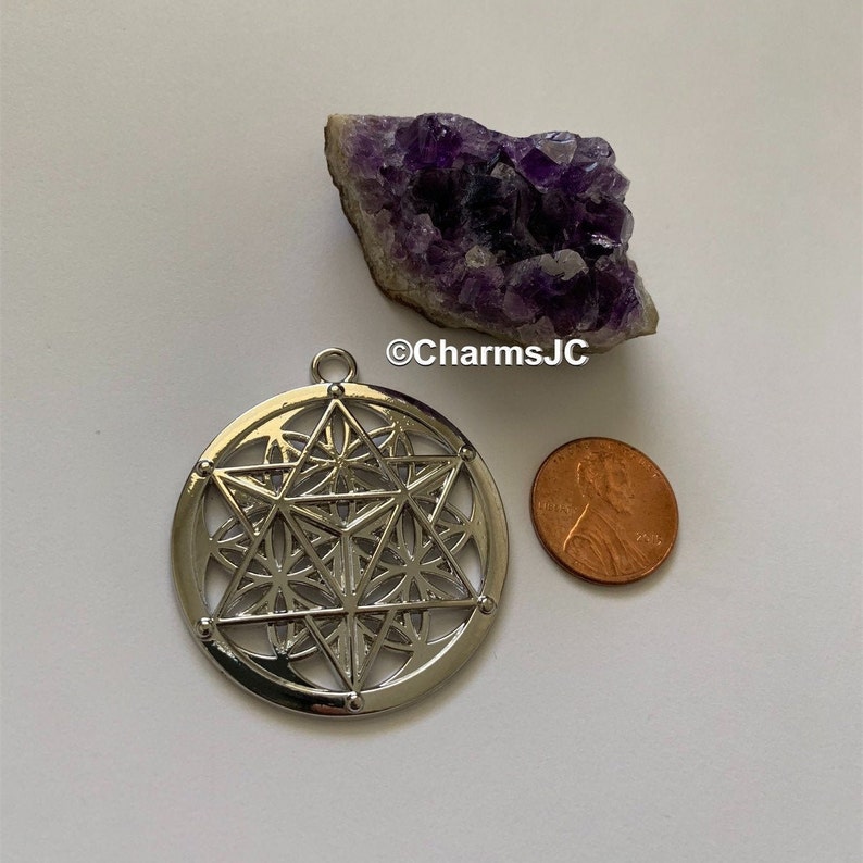 May include: Silver pendant featuring a geometric design with a star in the centre. The pendant is about the size of a UK penny.