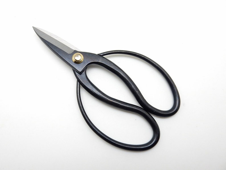 May include: Black pruning shears with a gold rivet. The shears have a curved handle and sharp blades.