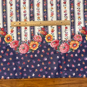 May include: White fabric with vertical blue stripes and a floral pattern. The floral pattern features red, yellow, and pink flowers. The fabric has a scalloped edge.
