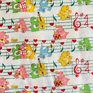 May include: White fabric with a repeating pattern of colorful cartoon bears playing musical instruments. The bears are pink, yellow, green, and blue. Musical notes, red hearts, and musical symbols are also present.