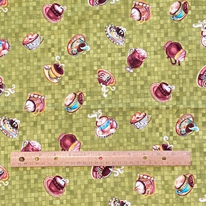 May include: Green fabric with a repeating pattern of various coffee cups and mugs with different designs and colors. The cups are on saucers and some have steam coming from them.