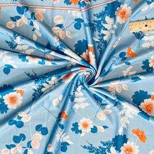 May include: Blue fabric with a white and orange floral print. The fabric has a subtle shimmer and a soft texture.