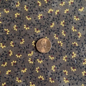 May include: Close-up of a brown fabric with a repeating pattern of small yellow flowers and dark green vines. A US penny coin is placed on the fabric for scale.