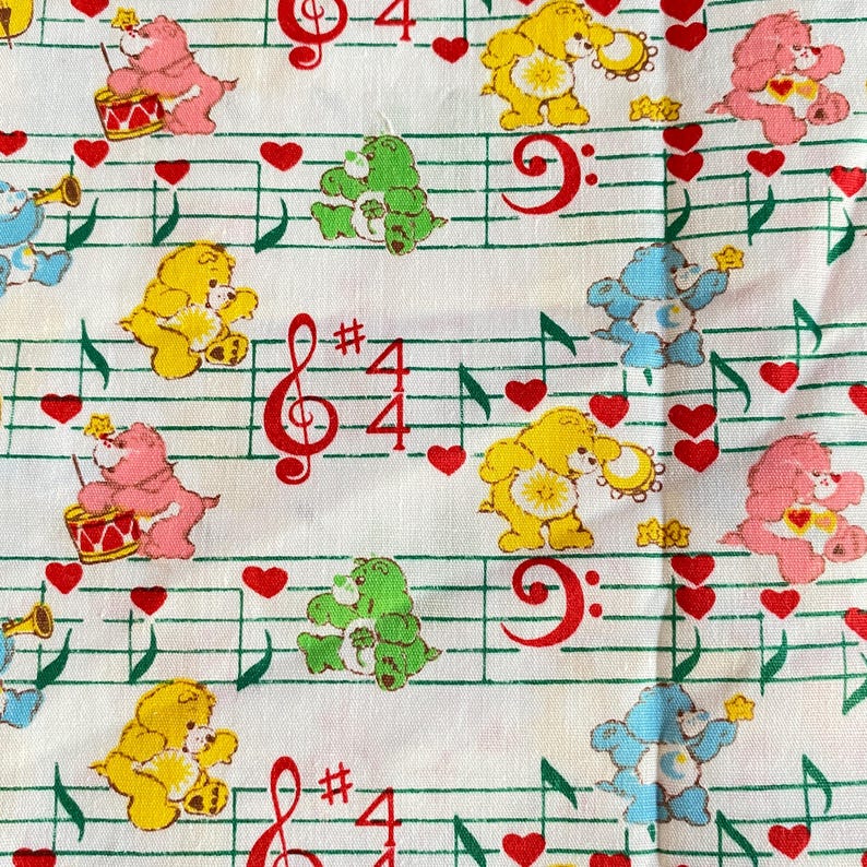 May include: White fabric featuring colorful cartoon bears, musical notes, and red hearts. The bears are in various colors, some playing instruments. Musical symbols and the number 4 are also present, creating a playful, musical theme.
