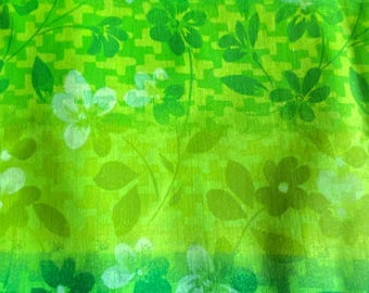 May include: A green fabric with a white floral pattern. The fabric has a gradient from a darker green to a lighter green.