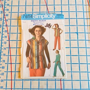 May include: Simplicity sewing pattern number 7614 for a sleeveless top and pants. The pattern includes three different looks, one with a striped top and orange pants, one with a blue top and blue pants, and one with a striped top and pink pants. The pattern is from Fabric World, 2645 Commercial S.E., Candalaria Terrace, Salem, Oregon 97302.