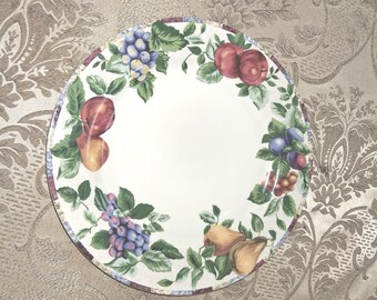 May include: White ceramic plate with a colorful fruit design. The plate features illustrations of grapes, apples, and pears, surrounded by green leaves. The rim has a decorative border.