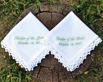 May include: Two white handkerchiefs with lace trim, embroidered with the text "Mother of the Groom October 14, 20" and "Mother of the Bride October 14, 2017".