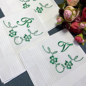 May include: Three white handkerchiefs with green embroidered shamrocks and letters. The letters are "R", "T", and "V".
