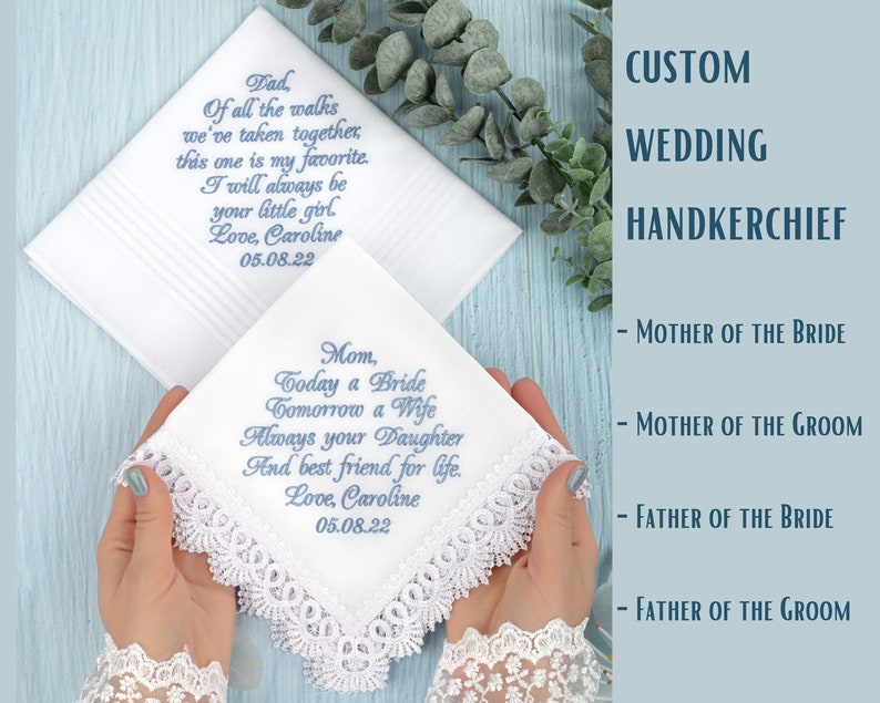 May include: Two white handkerchiefs with blue embroidered text. The top handkerchief has the text 'Dad, Of all the walks we've taken together, this one is my favorite. I will always be your little girl. Love, Caroline 05.08.22'. The bottom handkerchief has the text 'Mom, Today a Bride Tomorrow a Wife Always your Daughter And best friend for life. Love, Caroline 05.08.22'. Both handkerchiefs have lace trim.