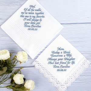 May include: Two white handkerchiefs with blue embroidered text. The top handkerchief has the text "Dad, Of all the walks we've taken together, this one is my favorite. I will always be your little girl. Love, Caroline 05.08.22". The bottom handkerchief has the text "Mom, Today a Bride Tomorrow a Wife Always your Daughter And best friend for life. Love, Caroline 05.08.22".