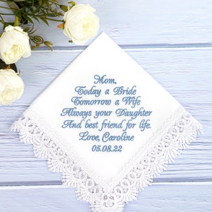 May include: White handkerchief with lace trim and blue embroidered text that reads "Mom, Today a Bride Tomorrow a Wife Always your Daughter And best friend for life. Love, Caroline 05.08.22".