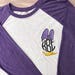 Daisy Duck Disney raglan sleeve tee. Monogrammed with the circle font on a purple and ice white raglan baseball sleeve tee