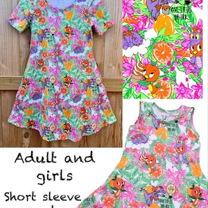 May include: A-line dress with a colorful pattern featuring cartoon characters, oranges, flowers, and the text "ONE LITTLE SPARK." The dress is available in short sleeve and sleeveless styles for adults and girls.