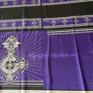 Może przedstawiać: Fioletowo-czarna tkanina z gotyckim wzorem krzyża. Tkanina przedstawia duży, szczegółowy krzyż z akcentami czaszki na fioletowym tle z promienistymi liniami. Czarne paski z wzorami krzyży i srebrnymi akcentami obramowują wzór.