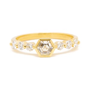 May include: A gold band ring with a hexagonal diamond in the center and smaller round diamonds on the band.