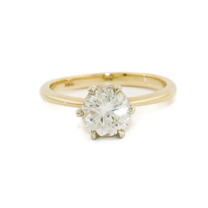 May include: A gold band engagement ring with a single round brilliant cut diamond.