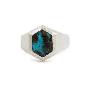 May include: A silver ring with a turquoise stone set in a hexagonal shape.