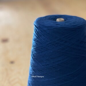 Op de afbeelding: Een spoel met diepblauwe garen, strak gewikkeld en klaar voor gebruik. Het garen heeft een textuur, waardoor het er uniek uitziet en aanvoelt.