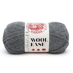 Puede incluir: Un ovillo de lana gris Wool Ease. La lana está envuelta en una etiqueta blanca con las palabras "Wool Ease" y el logotipo de Lion Brand Yarns. La etiqueta también presenta iconos de un sombrero, un suéter y otros símbolos de tejido.