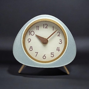 May include: A white and gold analogue clock with a triangular base and two legs. The clock face has black numbers and hands.