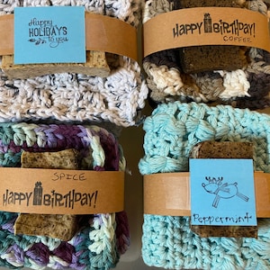 May include: Four crocheted dishcloths with brown paper gift tags and soap bars. The tags have the text "Happy Holidays to you", "Happy Birthday! Coffee", "Happy Birthday! Spice", and "Peppermint" with a reindeer illustration.