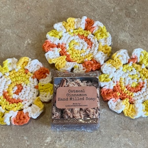 May include: Three crocheted coasters in white, yellow, and orange, with a bar of oatmeal cinnamon hand-milled soap in the center. The soap label reads "Oatmeal Cinnamon Hand Milled Soap" and "Made by LittleGemCreations".