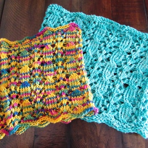 May include: Two crocheted dishcloths, one in a bright yellow, green, blue, and pink pattern and the other in a solid turquoise blue.